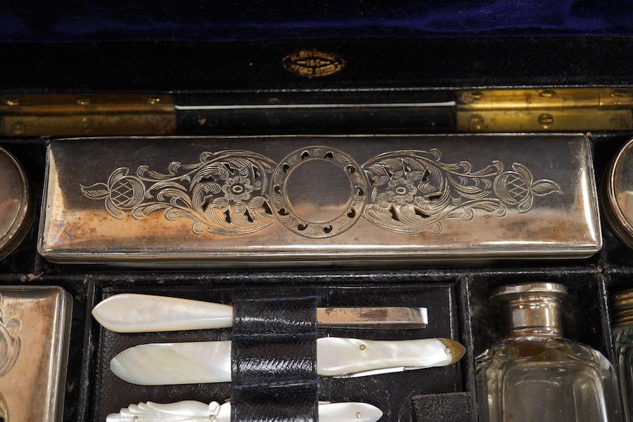 A Victorian leather vanity case with fitted interior to include white metal mounted glass bottles and mother of pearl mounted implements, with key, 27.5cm wide. Condition - fair, handle broken